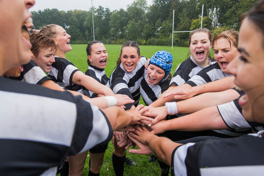 Team of female rugby players cheering a yell during a game.
