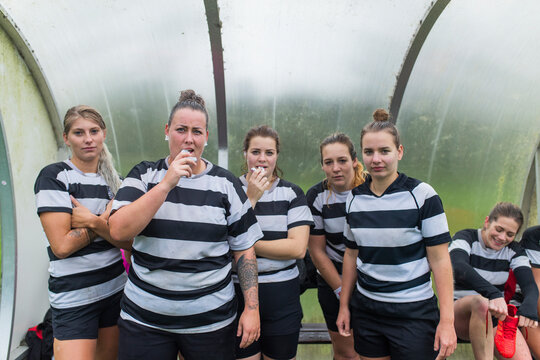 Five female rugby players are looking tough at the camera, stand