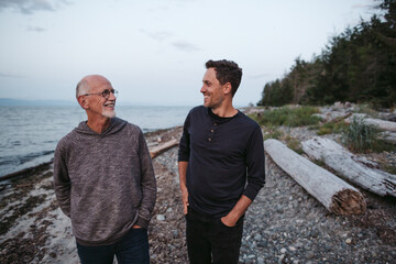 Father and grown son talking together on the beach.