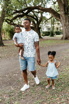 A beautiful African American family walking in the park. A father walking with his kids.