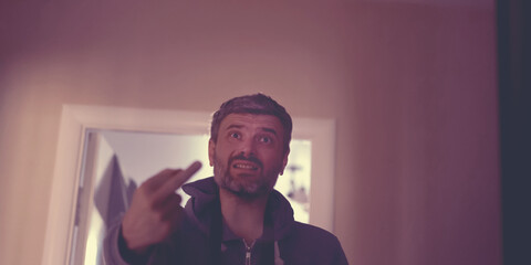 angry man show middle finger of hand fuck you sign in room of residential house