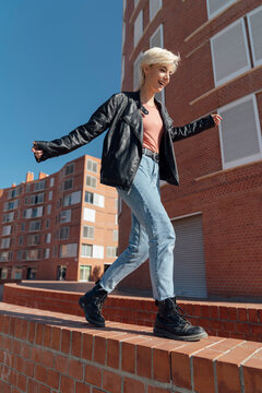 Young Rebel Teenager Woman Walking and Balancing on a Brick Wall