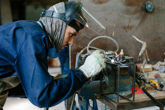Man melting a bronze sculpture with a blowtorch in a foundry