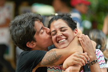 Affectionate Hispanic hipster couple kissing on street