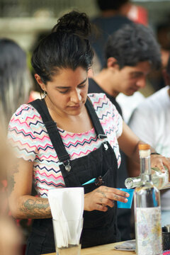 Female Hispanic bartender pouring mezcal drink
