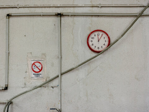 Wall with a clock and a non-smoking poster.