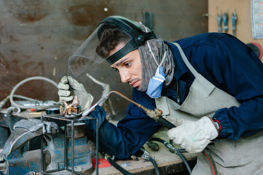 Man using a blowtorch in a foundry