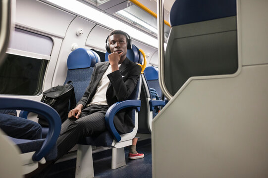 Young businessman sitting on the train using mobile phone