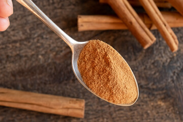 Ceylon cinnamon powder on a spoon, with cinnamon sticks