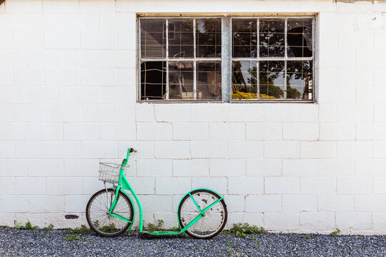 Green Amish pedal less bicycle leaned against a painted brick wall