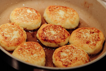 Cooking process of delicious fried syrniki close-up in the pan. Traditional in Ukraine, Belarus and...