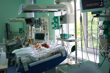 Reviving apparatus attached to a baby lying on a hospital bed