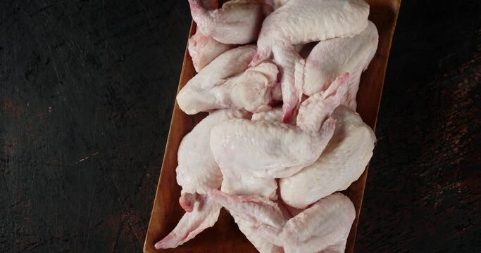 A wooden plate with raw chicken wings rotates. 
