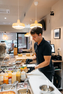 Waiter filling a poke bowl with food