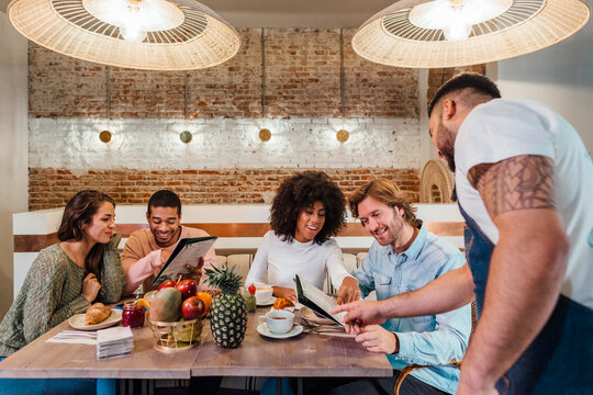 Waiter helping diverse friends to make order