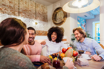 Multiethnic friends laughing at joke in cafe