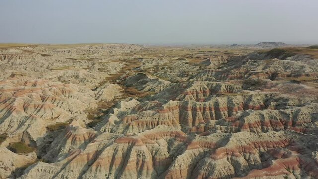 Aerial 4K video of South Dakota badlands with colorful canyons and rock formations. Drone shot moving left and rising up.