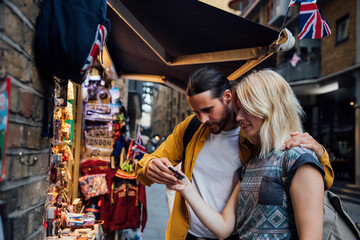 Young couple of tourists looking at souvenirs on a stall