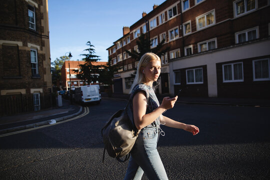 Girl walking on the street holding her cell phone
