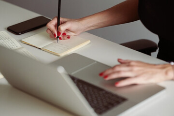 Unrecognizable reporter using laptop and making notes