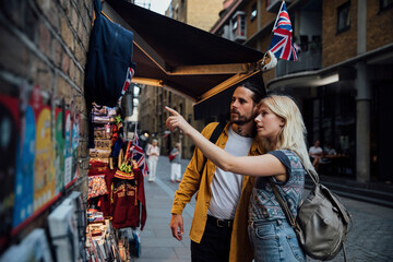 Young couple of tourists looking at a souvenir stall in London