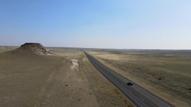 Aerial 4K video of cars driving along road to nowhere in dry grassland