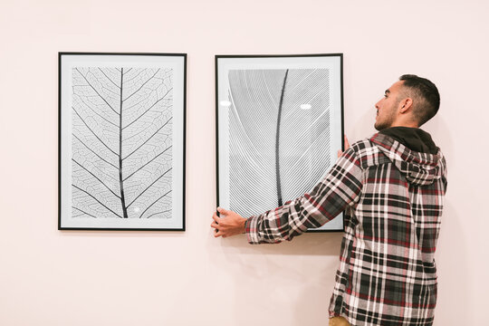 Young adult attaching photographs on wall