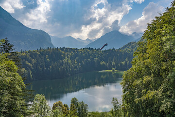 Fototapeta na wymiar nice senior woman riding her electric mountain bike above the Freiberg Lake and a big ski flying hill in the Allgau Alps near Oberstdorf, Bavaria, Germany 