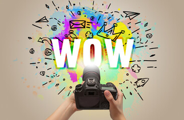 Close-up of a hand holding digital camera with abstract drawing and WOW inscription