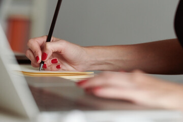 Woman with red nails taking notes.