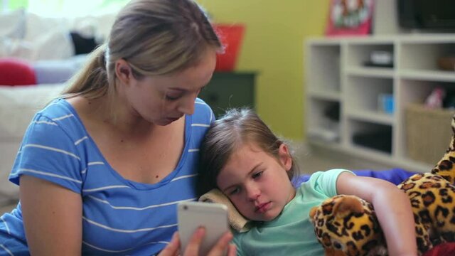 MS of a mother comforting her sick daughter as they have a video call with a doctor.