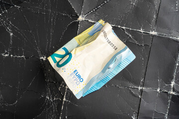 Crumpled twenty euro banknote on crumpled black wrinkled paper