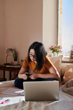 Student sitting with laptop on bed