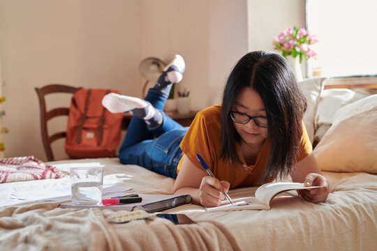 Asian student drawing in notebook