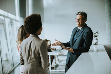 Multiethnic business people using digital tablet while standing in the office