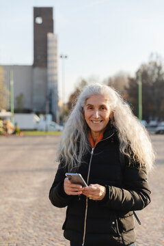 Happy Senior Woman Looking at Camera with Cellphone in Hand
