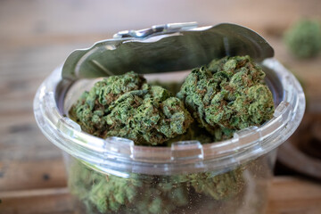 Cannabis in an open plastic jar with a pop-top tin lid - close up