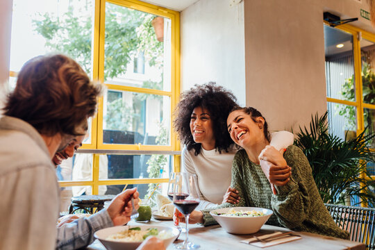 Multiethnic friends laughing at joke in cafe