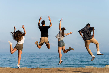 Happy friends jumping for joy by the sea