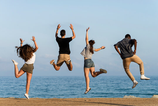 Happy friends jumping for joy by the sea