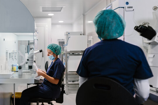 Biologists working on microscope in IVF laboratory