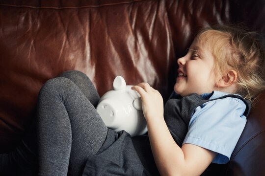 Schoolgirl putting money in a piggy bank
