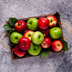 Ripe red and green apples in wooden box.