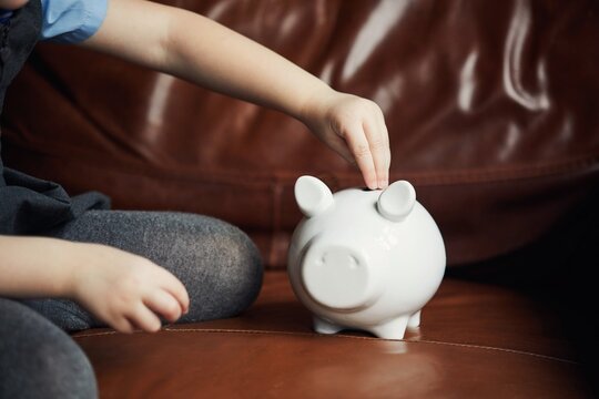 Schoolgirl putting money in a piggy bank