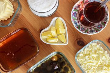 Top view of Turkish breakfast on wooden background. Tea, olive, butter, honey, cheese, sugar and lemon on the table.