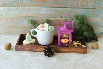 Fototapeta na wymiar Cup of coffee with meringue and dessert, Christmas decor, snowman, lantern with a burning candle, on a wooden table, the concept of home comfort, congratulations on the winter holidays