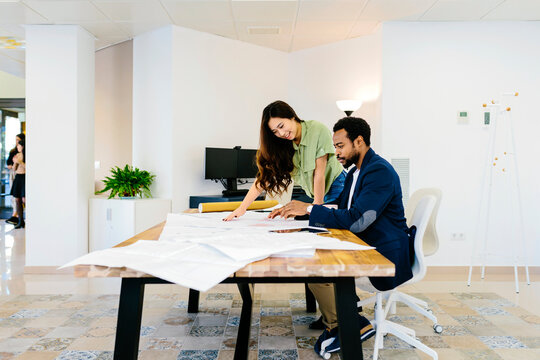 Diverse modern colleagues at table with drafts