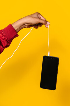 Closeup shot of woman hand holding a smartphone by the cable