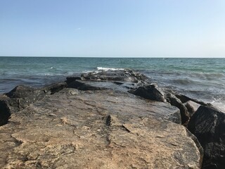 Rocks leading into the ocean with waves crashing against it. 