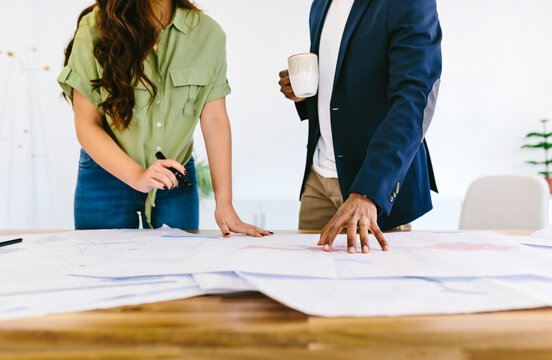 Crop colleagues working with paper drafts